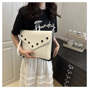 Close-up of white envelope clutch bag with metal eyelet trim and wristlet strap