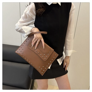 Close-up of brown envelope clutch bag featuring silver square studs and leather handle