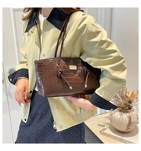 Détails de la texture crocodile marron foncé et des dorures sur ce grand sac cabas