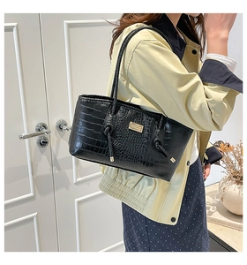 Detail of black crocodile texture on tote bag with elegant gold metal logo plate