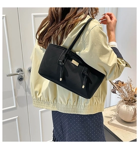 Close-up of black quilted hobo bag with gold metal plate and stylish knot handle detail