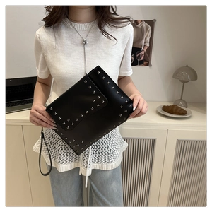 Detail of black matte PU leather envelope clutch featuring silver square rivet accents