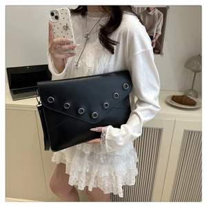 Detail of black PU leather envelope clutch featuring stylish silver metal eyelets