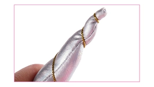 Macro detail of pink satin unicorn horn with gold spiral thread for party costumes