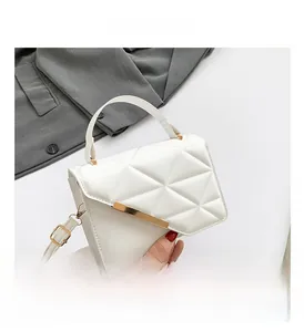 Detail view of white geometric quilted bag with gold metal trim and adjustable strap
