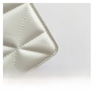 Detail shot of white quilted faux leather texture with neat stitching on square bag