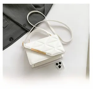 Flat lay of white quilted faux leather bag with gold trim and grey blazer accent