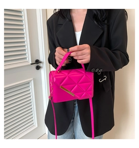 Model wearing a rose pink quilted crossbody bag with gold metal trim and leather strap