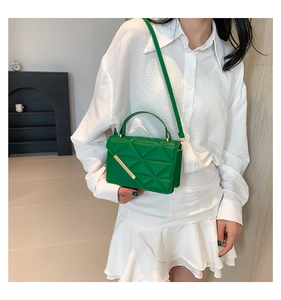Detail of green square bag with triangular quilted texture and gold metal bar accent