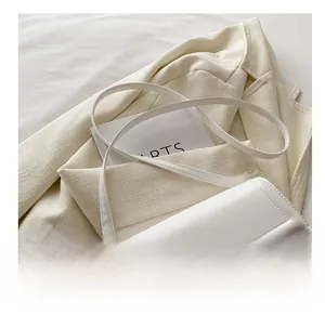 Detail of white leather crossbody bag with visible stitching and gold hardware