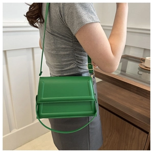 Detail of green minimalist crossbody bag showing rectangular embossed leather texture