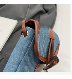 Detail of denim shoulder bag featuring brown leather drawstring and resin horn toggle closure