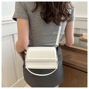 Close-up of a white matte leather crossbody bag showing rectangular stitching details