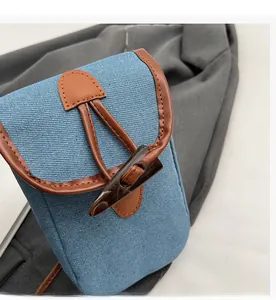 Detailed view of the vintage horn buckle closure and blue denim fabric of the crossbody bag