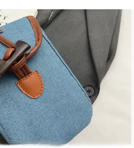 Detail of blue denim fabric with brown faux leather flap and horn buckle on a retro bag