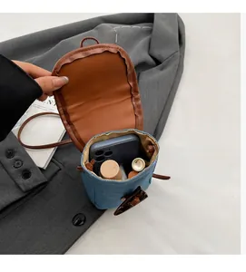 Detail showing inner space of denim crossbody bag with horn buckle and leather trim