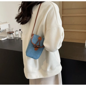 Borsa a tracolla in denim con finiture in pelle indossata da una modella per look casual