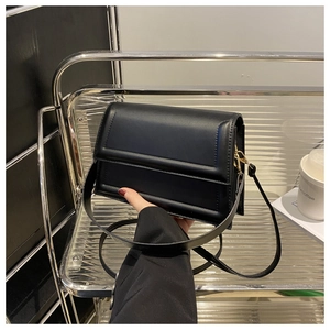 Detail of black faux leather crossbody bag with elegant gold metal hardware and embossed frame