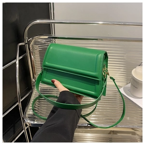 Detail of emerald green leather crossbody bag featuring gold hardware and flap closure