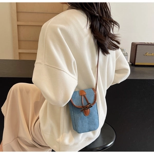 Dettaglio mini borsa a tracolla in denim con finiture in pelle marrone e fibbia in corno