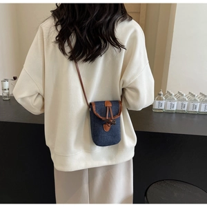 Dettaglio borsa per cellulare in denim blu con fibbia in corno e tracolla in pelle