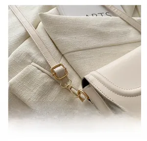Détail de la bandoulière réglable avec finitions dorées sur un sac crème chic