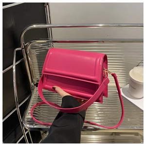 Detail of rose red square crossbody bag with wide strap and gold metal buckle