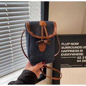 Dettaglio della borsa a tracolla in denim e pelle con chiusura a alamaro classica