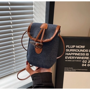 Dettaglio di borsa a tracolla in denim vintage con chiusura a alamaro e finiture in pelle