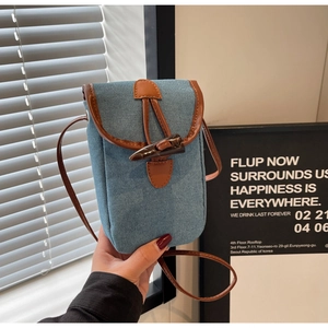 Dettaglio della mini borsa in denim blu con chiusura ad alamaro e finiture in cuoio
