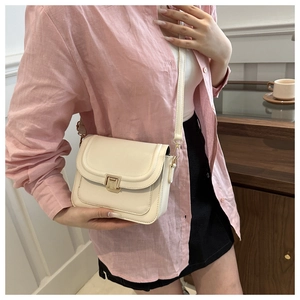Sac bandoulière chic en cuir crème avec fermoir doré présenté dans un style de vie