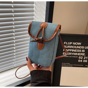 Dettaglio borsa porta cellulare in denim azzurro con finiture in pelle marrone e alamaro
