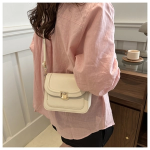Vue détaillée du petit sac carré crème avec fermoir doré porté en bandoulière