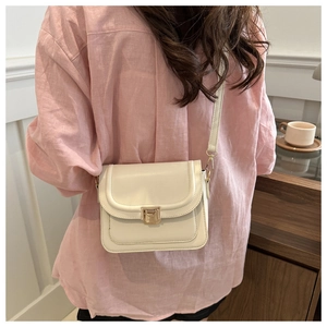 Détail d'un sac selle en similicuir crème avec boucle dorée porté par un modèle