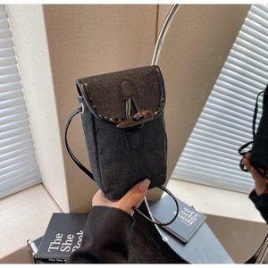 Close-up of denim crossbody bag featuring a wooden horn buckle and black leather trim