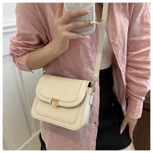 Selfie miroir montrant un sac selle en similicuir crème avec boucle dorée élégante