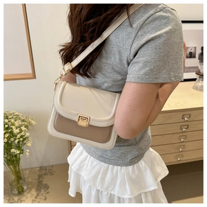 Sacoche beige minimaliste avec boucle dorée portée par un mannequin en intérieur doux