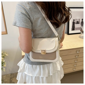 Sac bandoulière carré à boucle dorée porté par un mannequin dans un décor d'intérieur épuré
