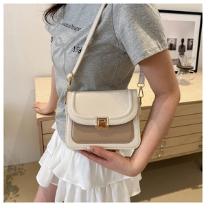 Gros plan d'un sac bandoulière minimaliste bicolore avec une boucle dorée sur un mannequin