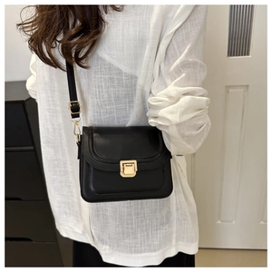 Détail du petit sac bandoulière noir minimaliste avec boucle dorée porté par le mannequin