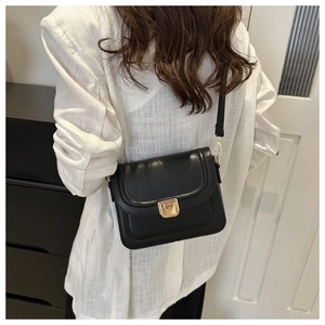 Détail d'un sac bandoulière noir avec fermoir en métal doré et sangle réglable