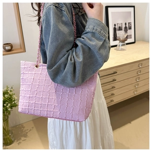 Détail du sac cabas rose avec texture à carreaux et bandoulière chaîne dorée