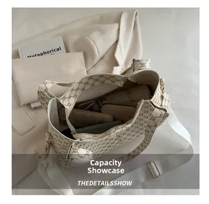 Dettaglio della grande capacità della borsa tote beige con monogramma e oggetti quotidiani