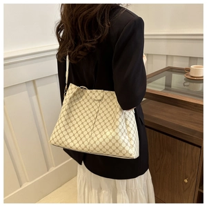 Dettaglio borsa tote color crema con motivo a rombi scuri indossata a tracolla