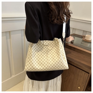 Dettaglio di una grande borsa tote crema con motivo a catena geometrica e tracolla larga
