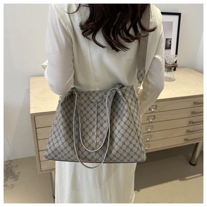 Dettaglio della borsa tote grigia monogram con tracolla in tessuto su una modella
