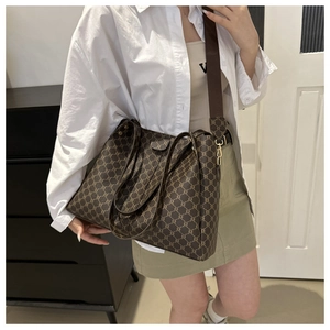 Dettaglio di una grande borsa tote vintage marrone con motivo monogramma e tracolla larga