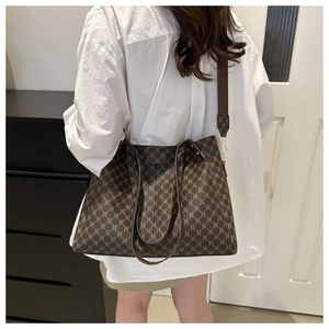 Borsa tote vintage marrone con motivo monogramma geometrico indossata a spalla