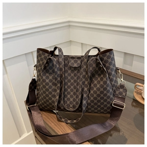 Dettaglio di borsa tote vintage con motivi a catena e ampia tracolla marrone sul tavolo