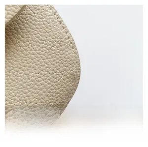 Close-up of beige grained leather texture and precision stitching on the handbag